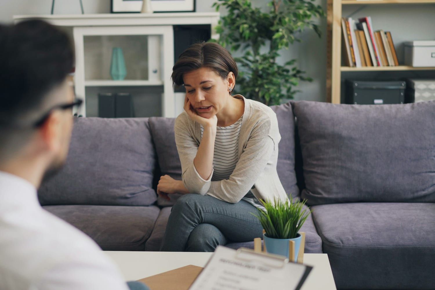 Een behandelaar, van achteren gezien, in gesprek met een cliënt op een bank.
