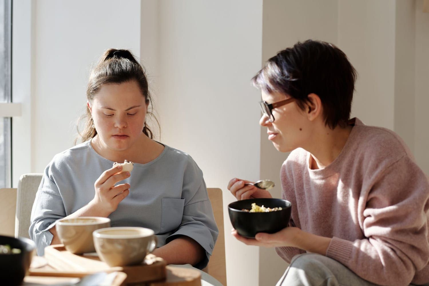Twee vrouwen aan het ontbijt; een van hen heeft het syndroom van Down.